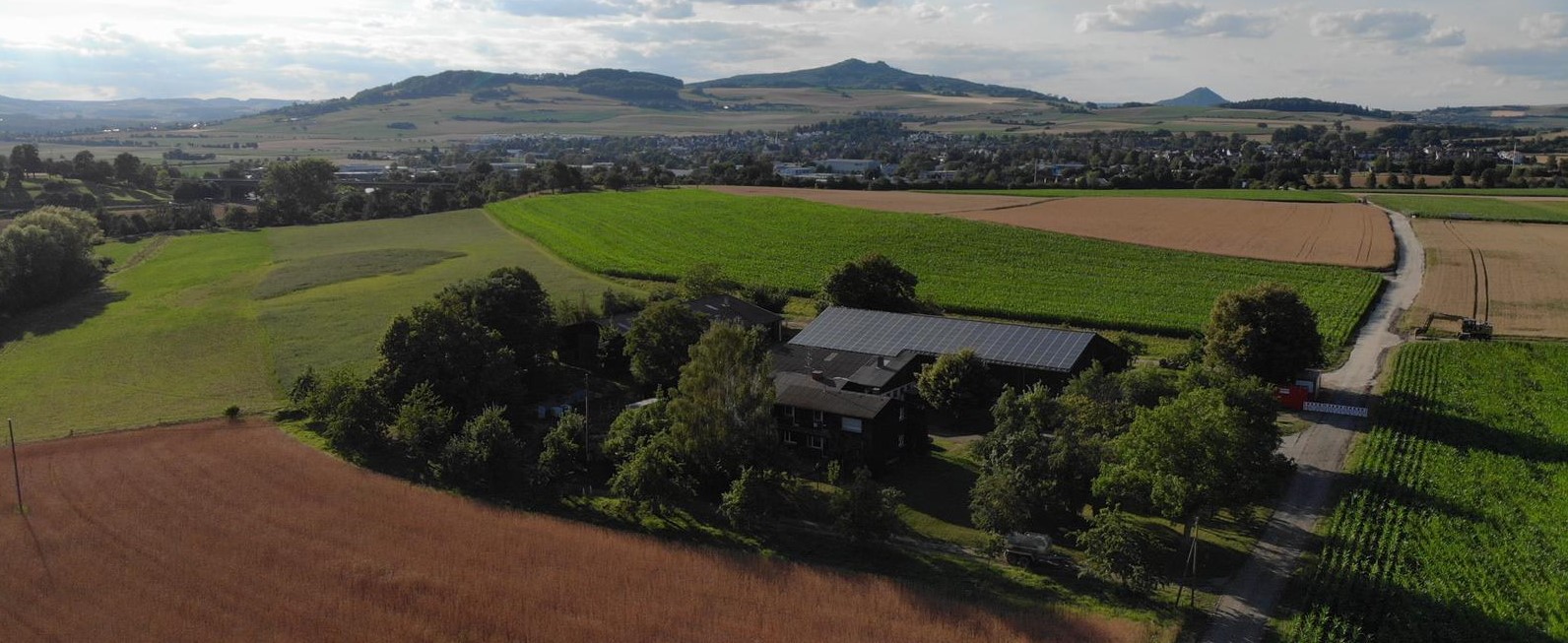 Luftaufnahme des Betriebs Biolandhof Georgshof mit Feldern und Hohem Twiel im Hintergrund