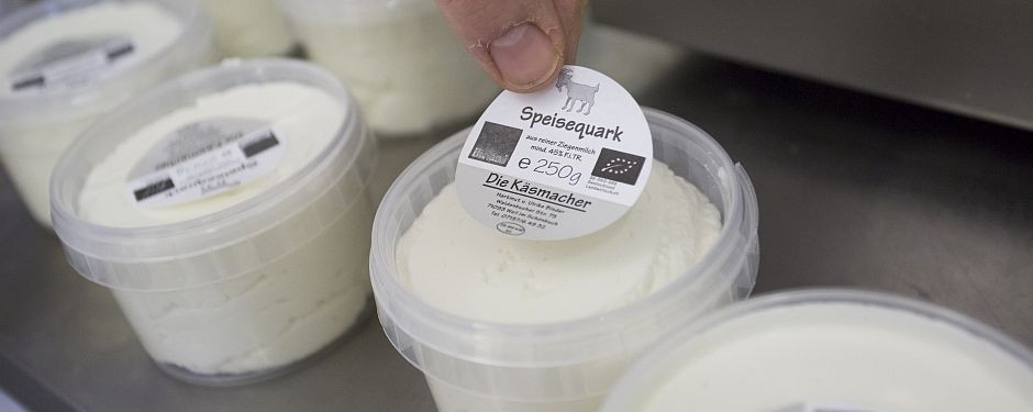Ein Etikett wird auf ein Becher Frischkäse geklebt