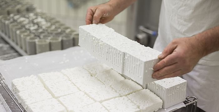 Die geschnittene Käsemasse wird aus dem Vorpressrahmen per Hand entnommen