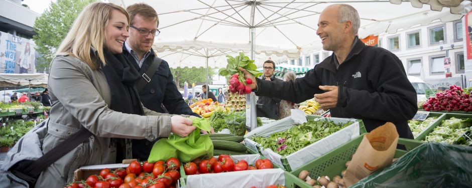 Marktszene; Kunden kaufen ein Bund Radieschen 